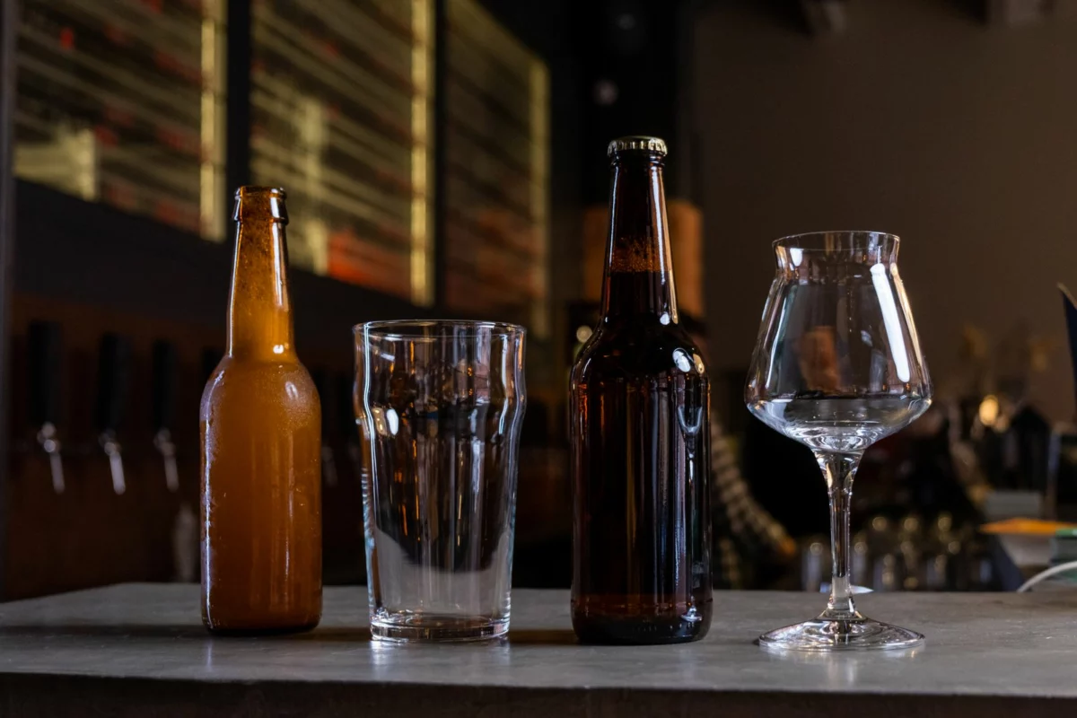 Bouteilles de bière et verre posés sur une table en bois, illustration de la gamme Grimbergen Cuvée Réserve en 75 cl